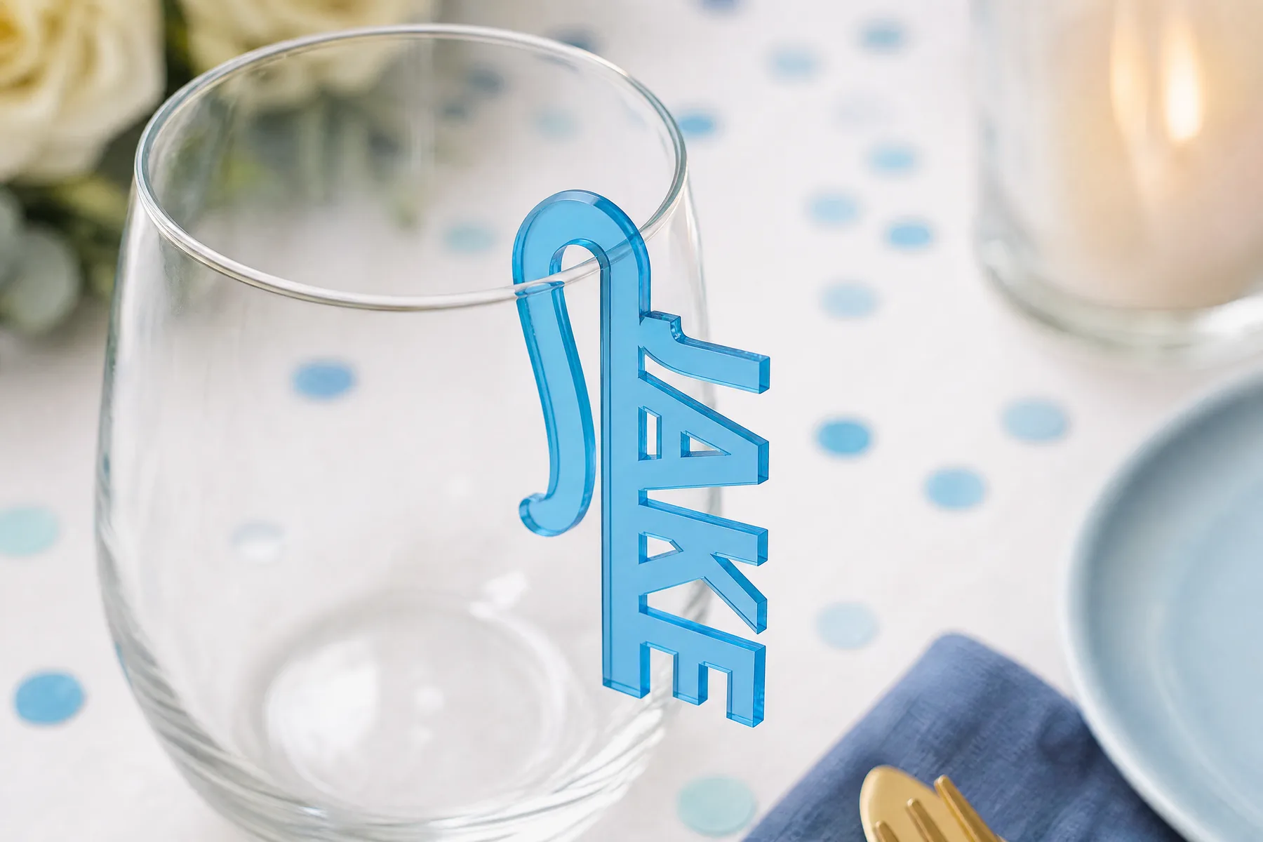 A laser-cut acrylic name clip sitting on the rim of a wine glass